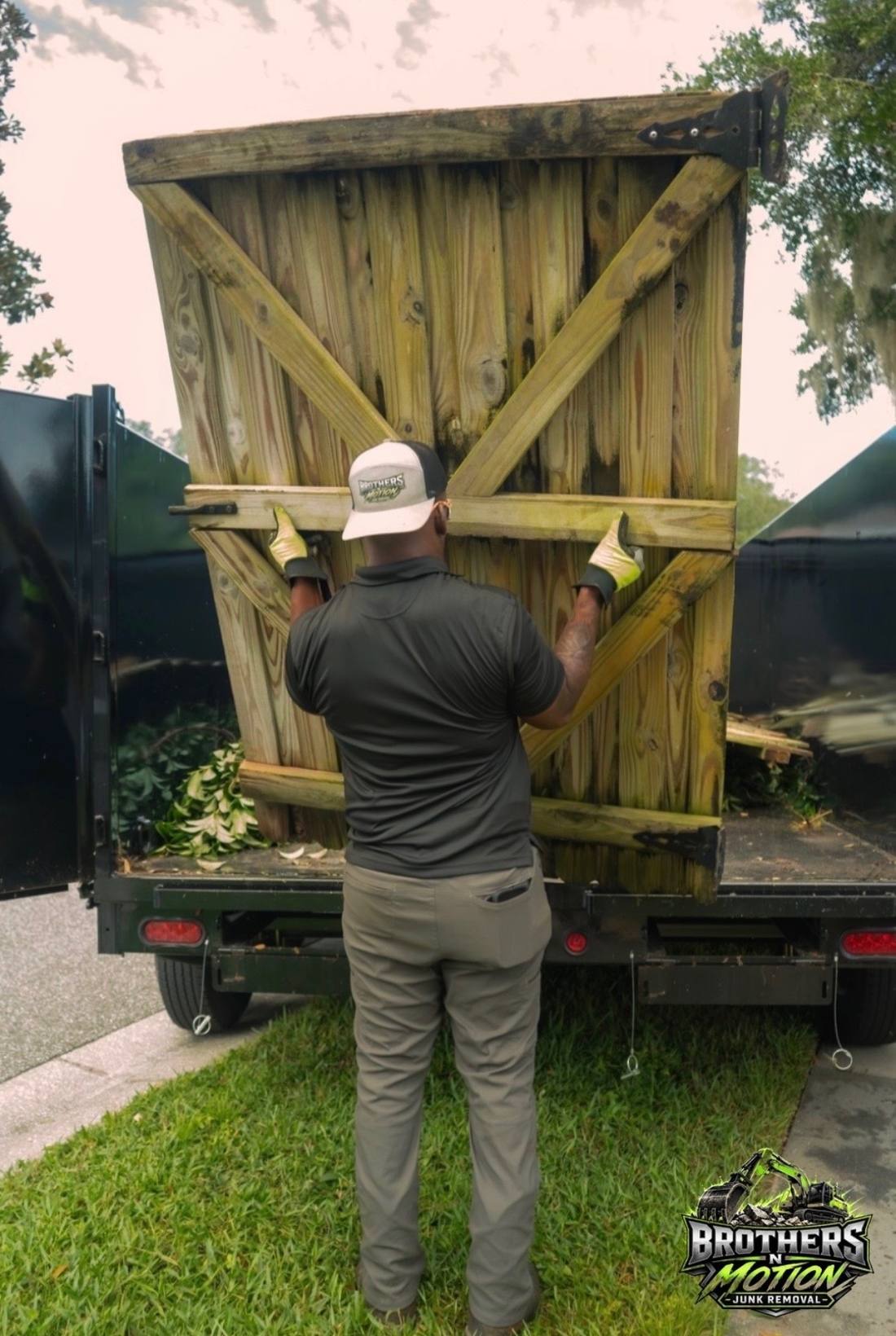 Crew member loading a fence panel into the dump trailer